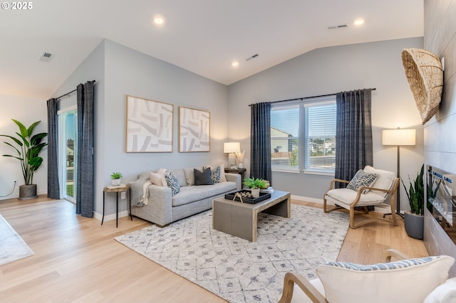 living room with light wood-type flooring, lofted ceiling, visible vents, and baseboards