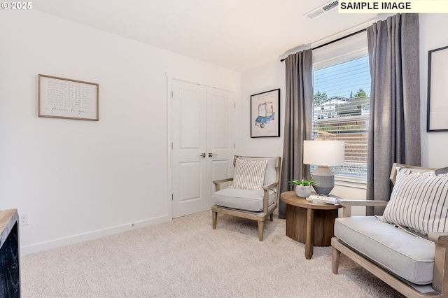 living area with light colored carpet, visible vents, and baseboards