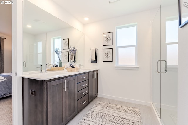 full bath featuring ensuite bathroom, a sink, baseboards, double vanity, and a stall shower