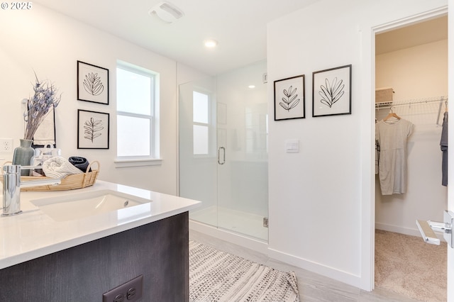 full bathroom featuring visible vents, vanity, baseboards, a spacious closet, and a stall shower