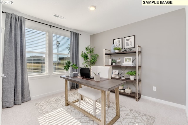 office area with light colored carpet, visible vents, and baseboards