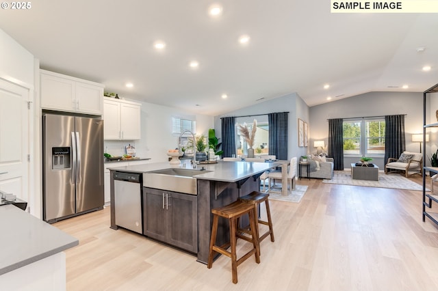 kitchen with open floor plan, stainless steel appliances, a sink, and lofted ceiling