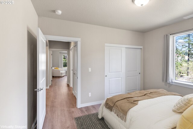 51013 Mckenzie Hwy, Vida, OR 97488 - bedroom featuring light wood-style floors, multiple windows, a closet, and baseboards