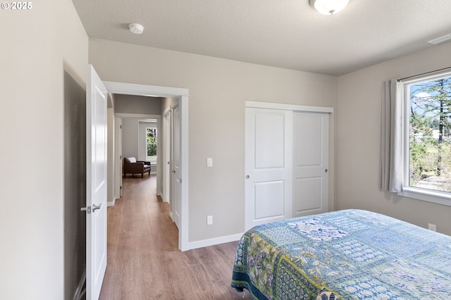 bedroom with a closet, wood finished floors, visible vents, and multiple windows