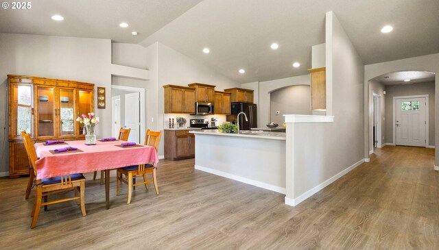 51013 Mckenzie Hwy, Vida, OR 97488 - kitchen with arched walkways, stainless steel appliances, lofted ceiling, a peninsula, and brown cabinetry