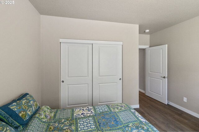 bedroom with baseboards, wood finished floors, a textured ceiling, and a closet