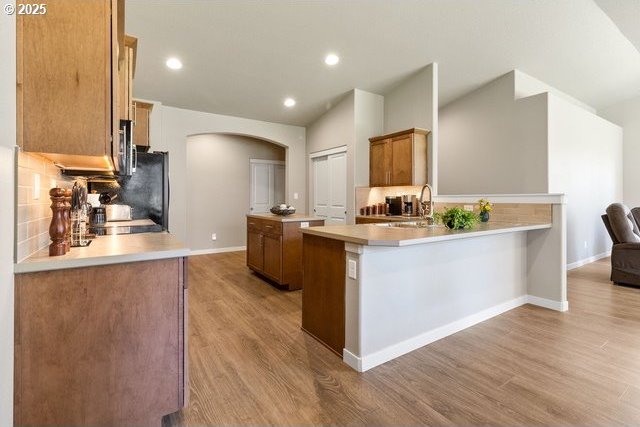 kitchen with arched walkways, a center island, a sink, and light wood-style floors