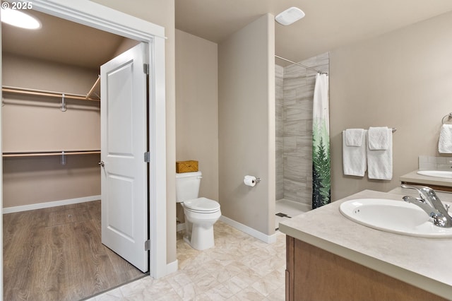 full bath with a spacious closet, toilet, vanity, and tiled shower