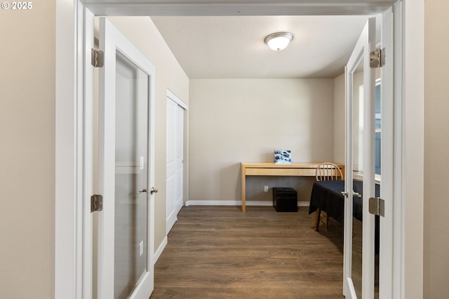 corridor featuring dark wood finished floors, baseboards, and french doors