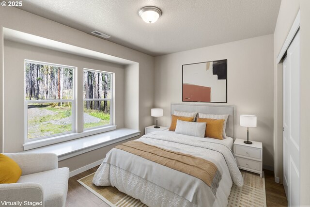 51013 Mckenzie Hwy, Vida, OR 97488 - bedroom with multiple windows, wood finished floors, a closet, and a textured ceiling