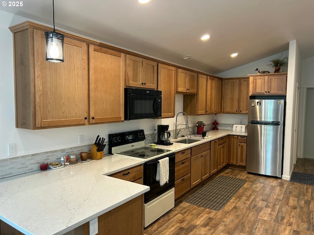 kitchen with a sink, a peninsula, freestanding refrigerator, black microwave, and range with electric cooktop