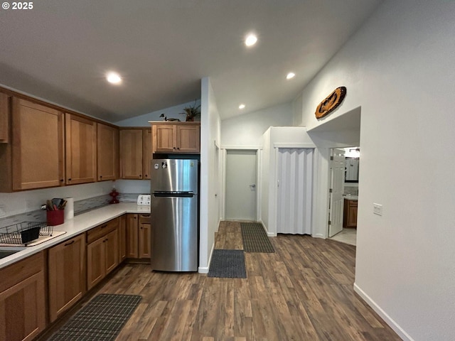 kitchen featuring freestanding refrigerator, lofted ceiling, dark wood-style flooring, and light countertops