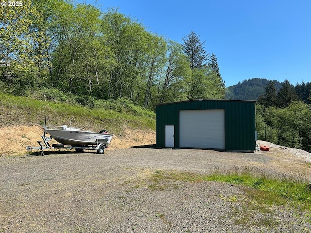 detached garage with driveway and a forest view