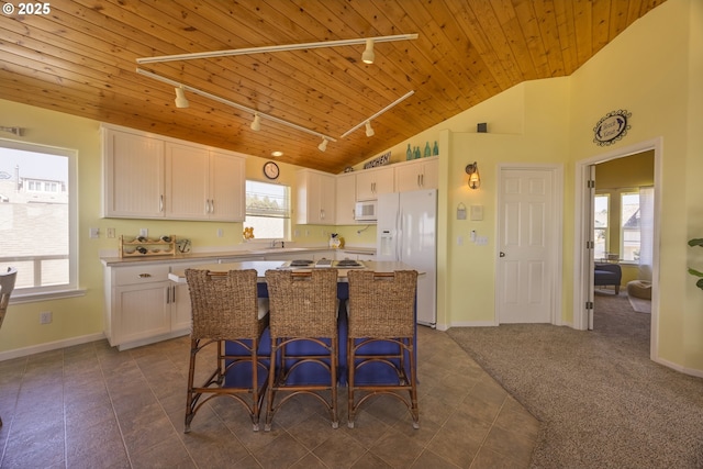 962 SW Waziyata Ave, Waldport, OR 97394 - kitchen with rail lighting, wooden ceiling, white appliances, white cabinets, and a kitchen island