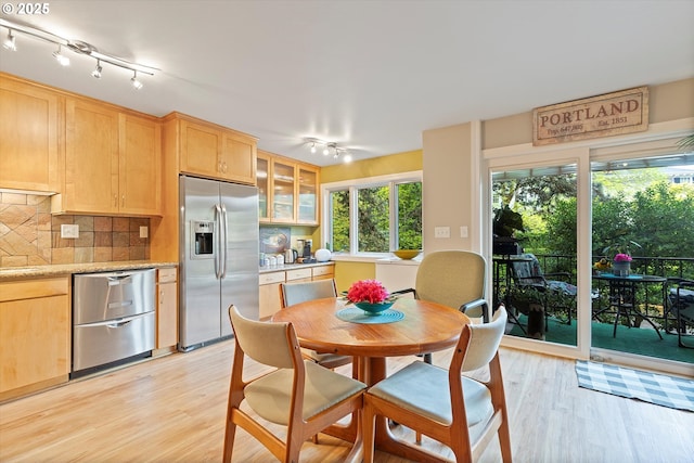 interior space with track lighting, light wood-type flooring, light brown cabinetry, and stainless steel appliances