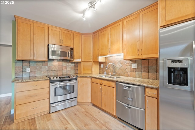 kitchen featuring a sink, appliances with stainless steel finishes, light brown cabinets, and light wood finished floors