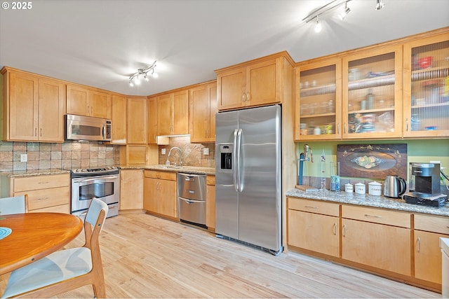 kitchen featuring light brown cabinetry, light stone countertops, appliances with stainless steel finishes, track lighting, and light wood finished floors