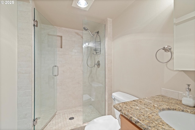 bathroom with toilet, a shower stall, and vanity