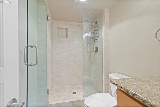bathroom with toilet, a shower stall, and vanity