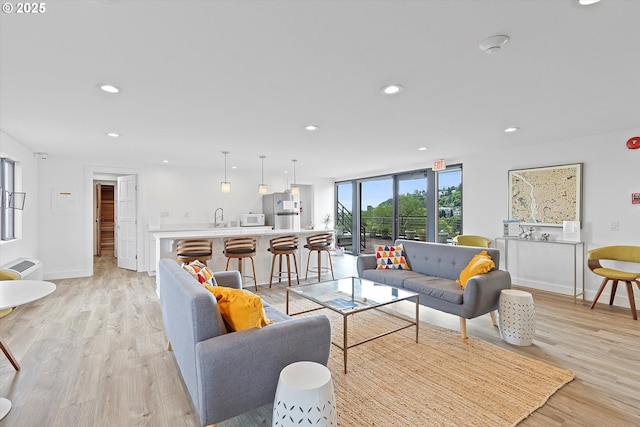 living area featuring recessed lighting, baseboards, and light wood finished floors