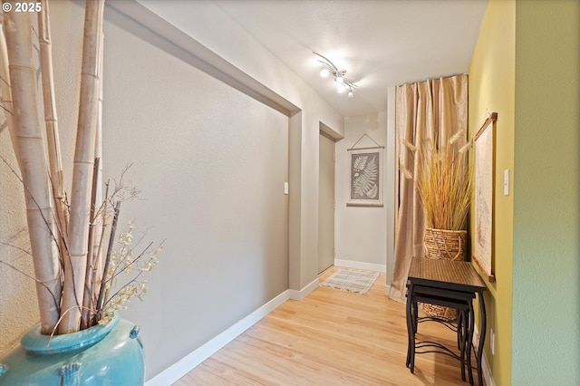 corridor with baseboards and light wood-type flooring