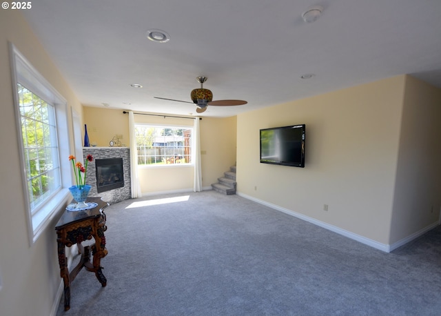 2525 Pine St, Seaside, OR 97138 - living area with carpet, baseboards, a ceiling fan, a stone fireplace, and stairs