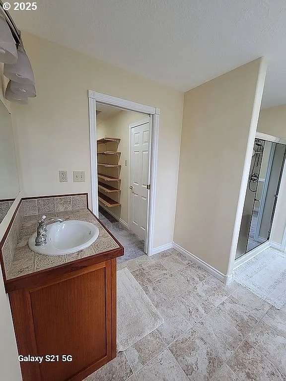 2525 Pine St, Seaside, OR 97138 - full bath with baseboards, a shower stall, vanity, and stone finish floors