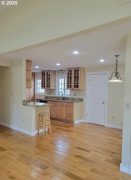 2525 Pine St, Seaside, OR 97138 - kitchen with baseboards, recessed lighting, light wood-style flooring, glass insert cabinets, and a sink