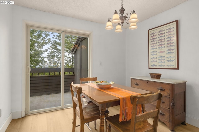 dining space with baseboards, light wood finished floors, a chandelier, and a textured ceiling