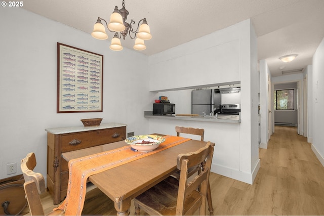 dining area with an inviting chandelier, light wood-style floors, baseboards, and a baseboard radiator