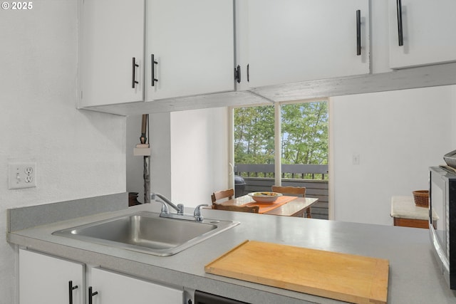 kitchen featuring white cabinets, light countertops, and a sink