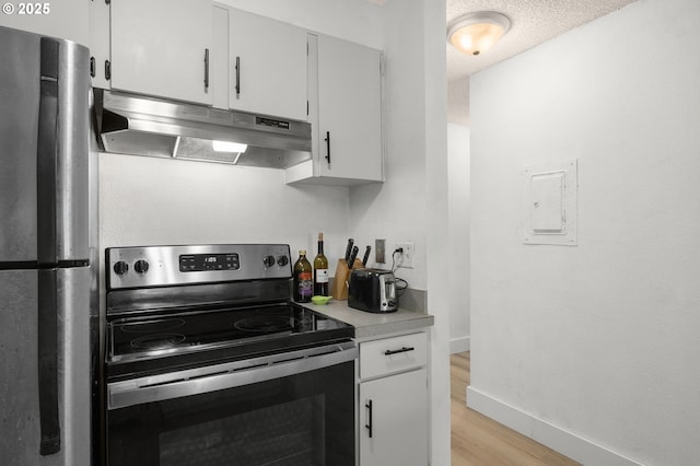 kitchen featuring under cabinet range hood, light wood finished floors, light countertops, baseboards, and appliances with stainless steel finishes