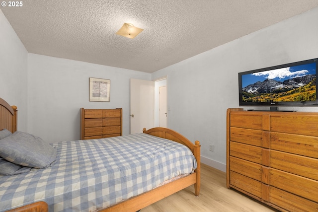 bedroom with light wood-style flooring, a textured ceiling, and baseboards