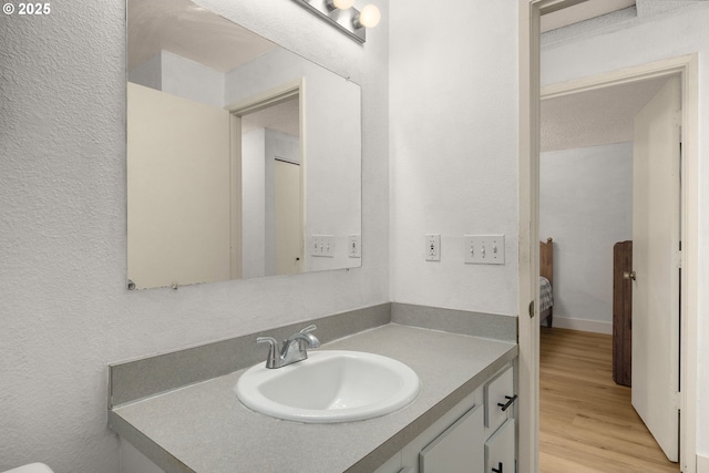 bathroom with vanity, a textured wall, and wood finished floors