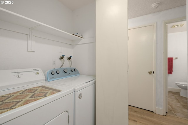 laundry room with washing machine and clothes dryer, light wood-type flooring, and laundry area