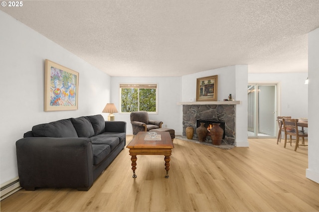 living area featuring a textured ceiling, wood finished floors, a fireplace, and a baseboard heating unit