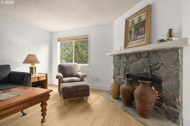 sitting room with a fireplace, a textured ceiling, and wood finished floors