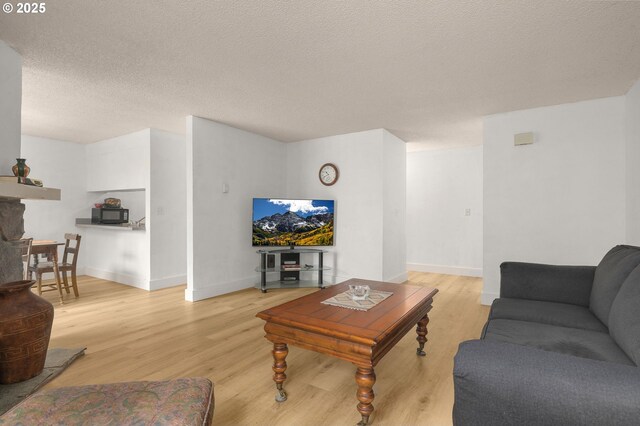 living area with light wood finished floors, a textured ceiling, and baseboards