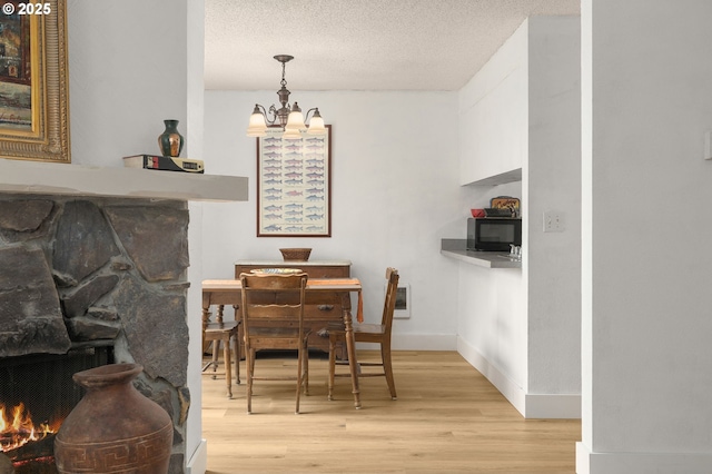dining space featuring baseboards, an inviting chandelier, light wood-style flooring, and a textured ceiling
