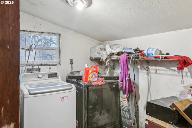 clothes washing area with a textured ceiling and washer and clothes dryer