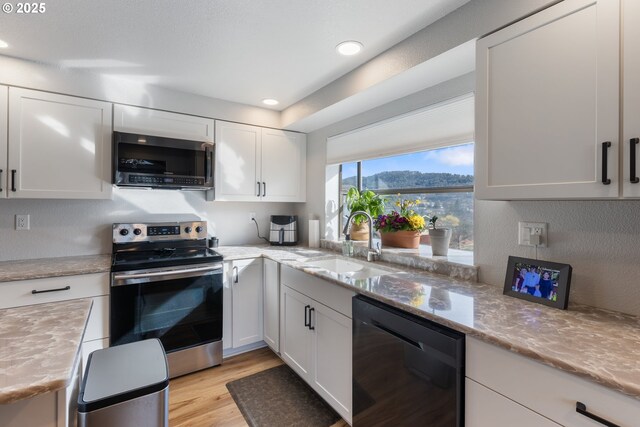 kitchen featuring light wood-style flooring, white cabinets, stainless steel appliances, and a sink