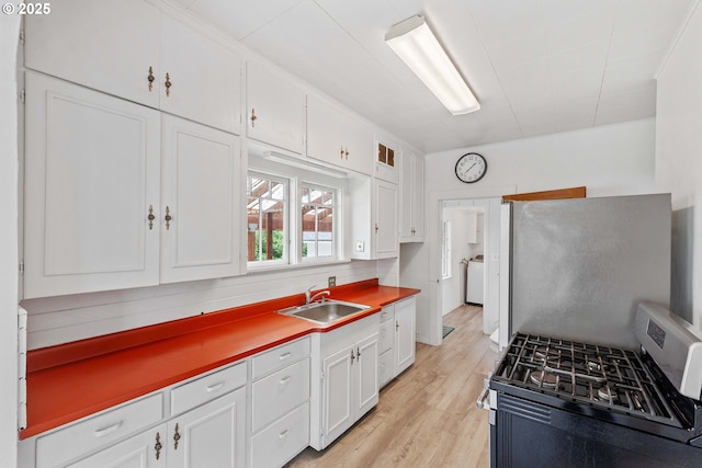 2479 Sherman Ave, North Bend, OR 97459 - kitchen featuring a sink, stainless steel gas range, washer / clothes dryer, refrigerator, and white cabinets