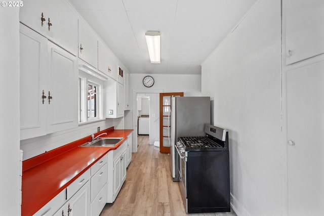2479 Sherman Ave, North Bend, OR 97459 - kitchen featuring gas range, a sink, white cabinets, washer / dryer, and light wood-style floors