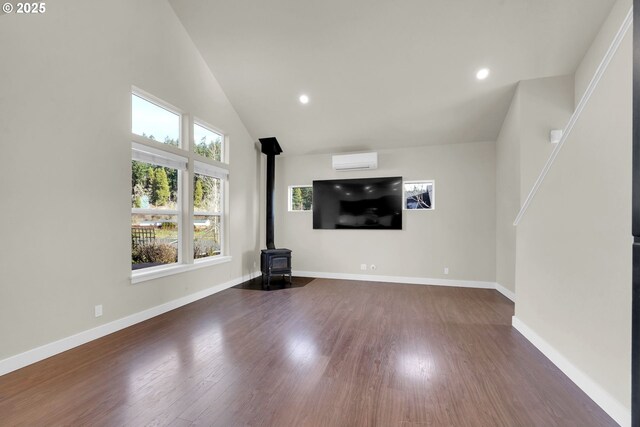 unfurnished living room with recessed lighting, wood finished floors, baseboards, a wall mounted air conditioner, and a wood stove