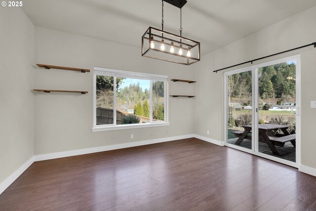 unfurnished dining area featuring a wealth of natural light, dark wood finished floors, and baseboards