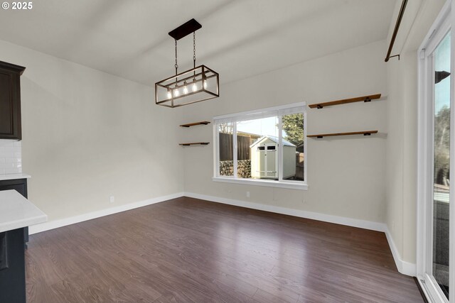 unfurnished dining area with baseboards and dark wood finished floors