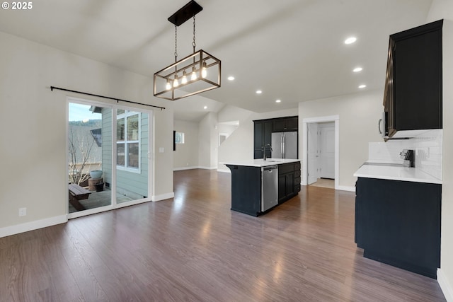 kitchen featuring dark cabinets, stainless steel appliances, dark wood-type flooring, open floor plan, and light countertops