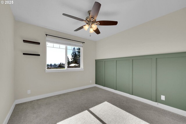 unfurnished bedroom with ceiling fan, a decorative wall, and carpet flooring