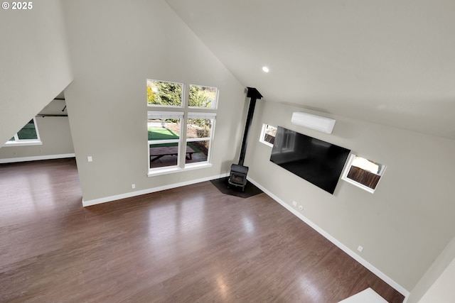 unfurnished living room featuring high vaulted ceiling, wood finished floors, a wood stove, and baseboards