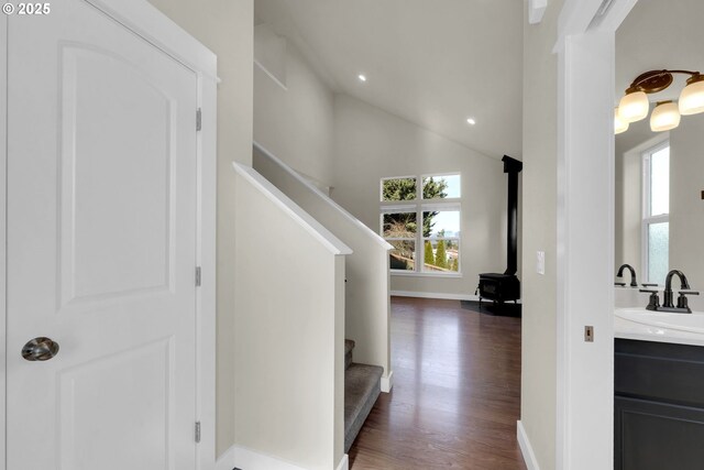 hall featuring dark wood finished floors, a healthy amount of sunlight, a sink, and stairs